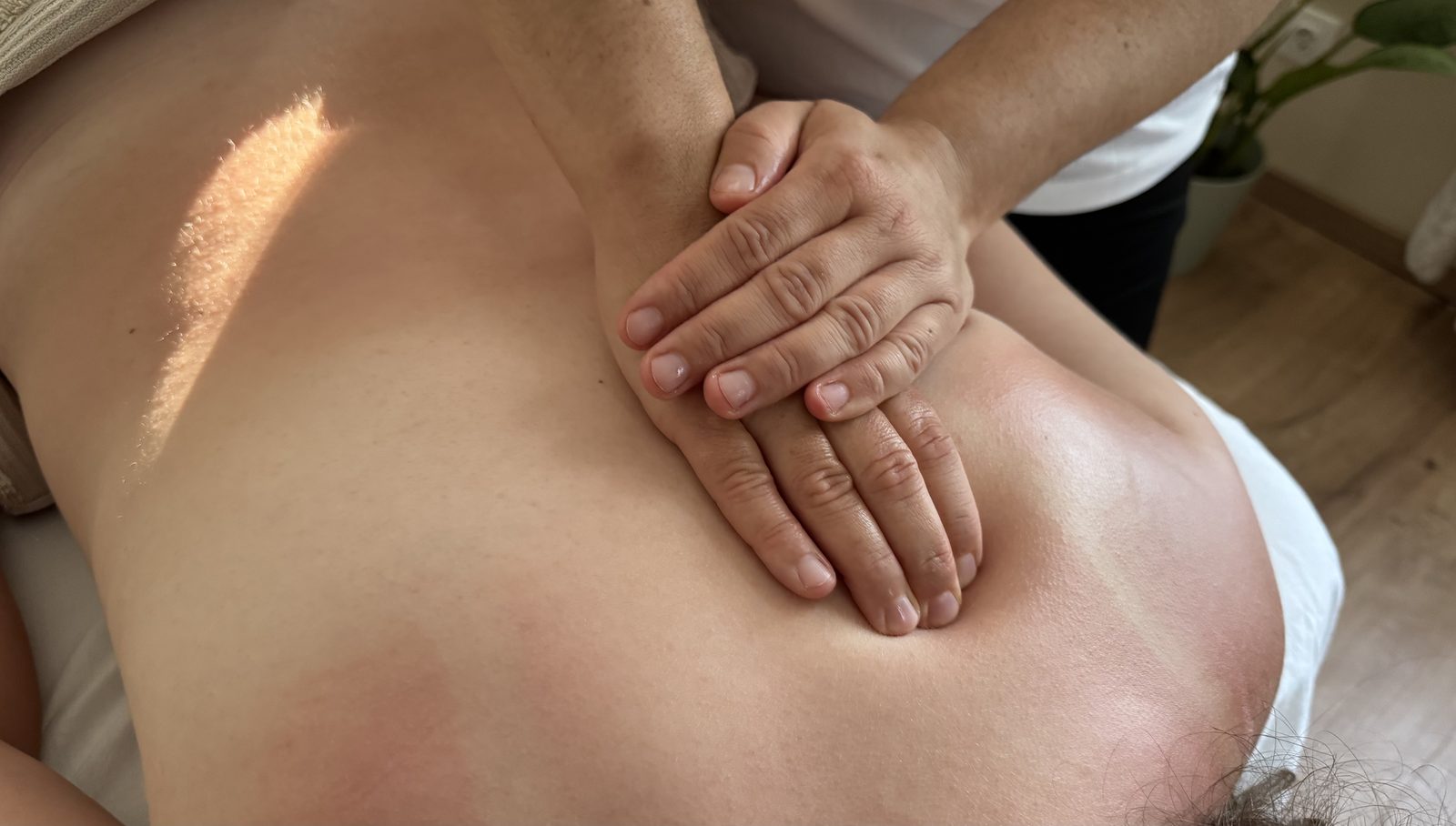 Masszázs közben: a terapeuta kezei a vendég hátán.
